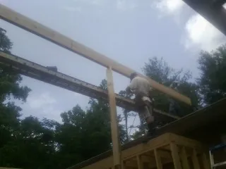 Carpenter setting a ridge beam over a new addition frame — Ice Dam Removal by Roofing Brothers in Hungerford
