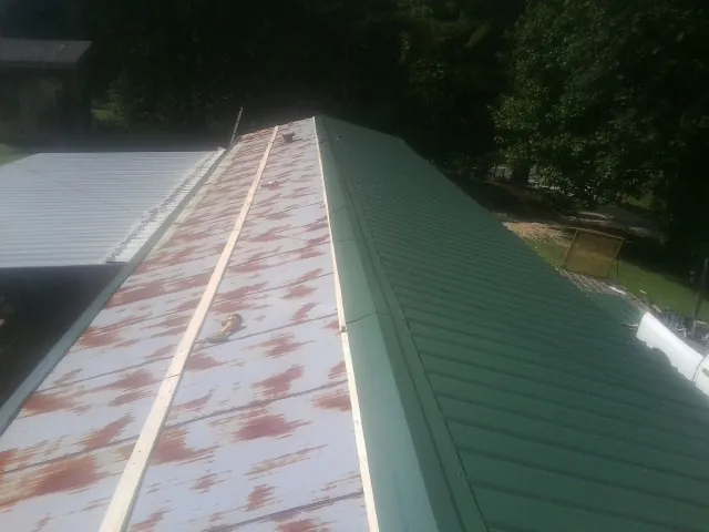 Old rusted panels beside newly installed green metal roofing — Wind Damage Roof Repair by Roofing Brothers in Hungerford