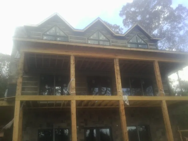 Dormers and porch framing on a large log home under construction — Roof Coating work by our crew in Hungerford