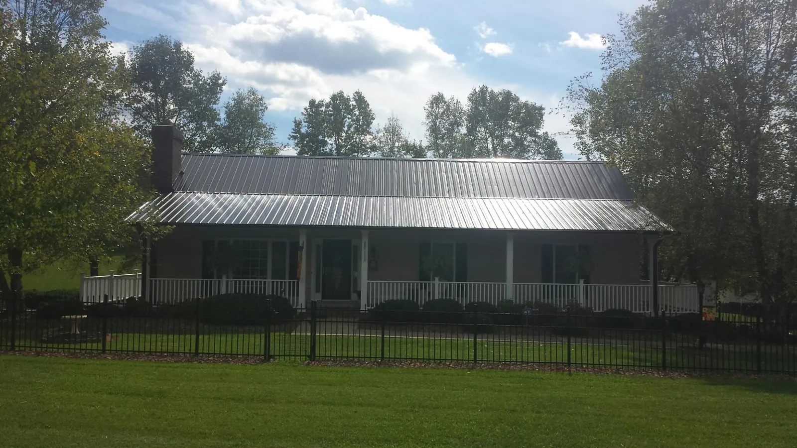 Gray metal roof on a brick ranch with a full width front porch — Gutter Guard Installation work by our crew in Hungerford