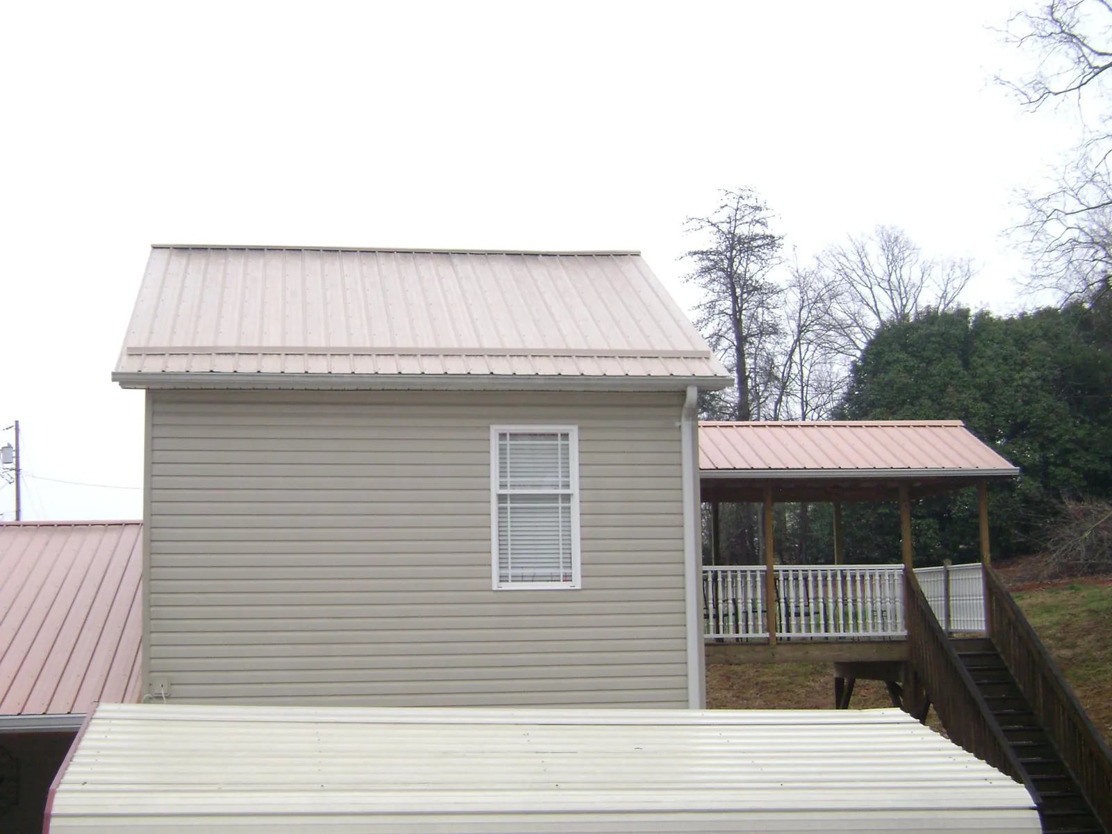 Tan metal roofs on a two story addition and attached porch, from a Roof Replacement job in Hungerford