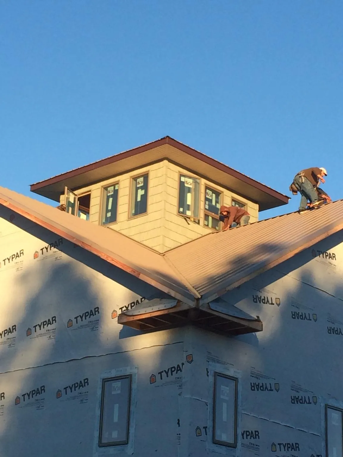 Roofers working around a rooftop cupola on a new metal roof at sunset — Roof Waterproofing in Hungerford by Roofing Brothers